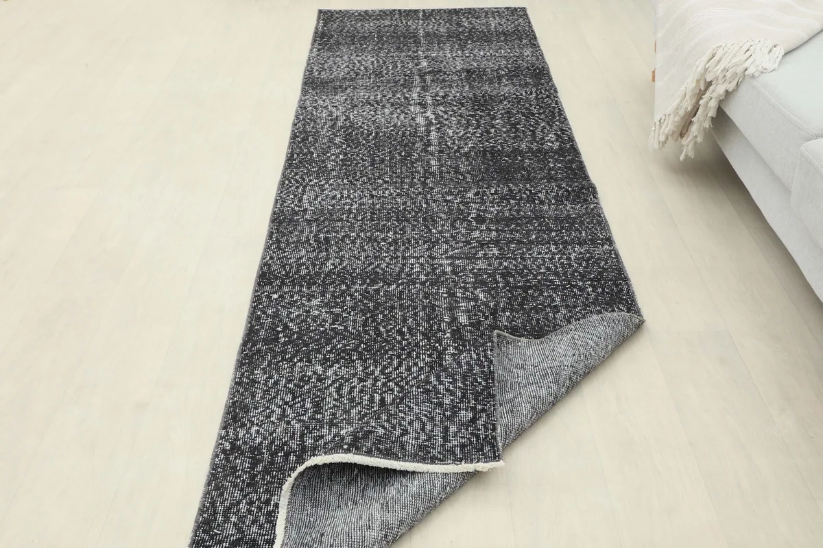 Runner rug partially folded, displaying both the top surface and the underside, showing its flexibility.