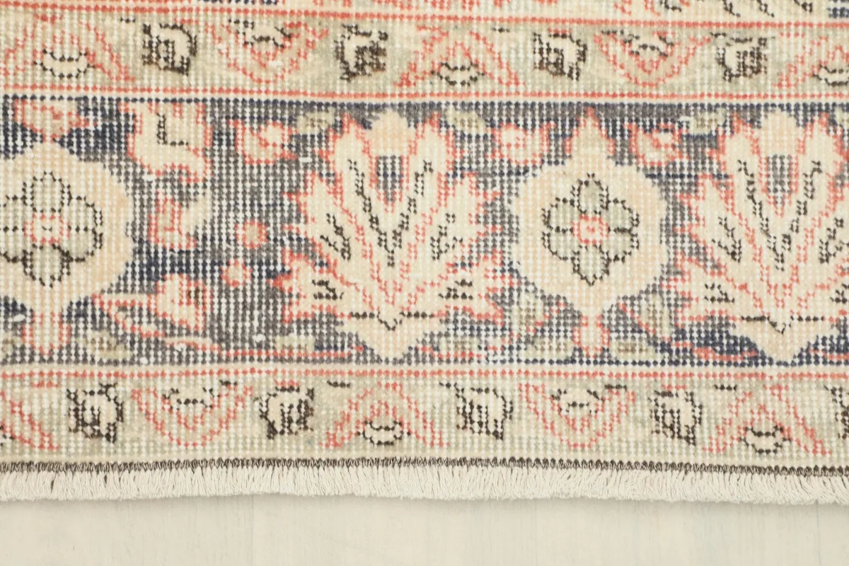 Detailed view of the rug's border design, showcasing navy, beige, and rust motifs.