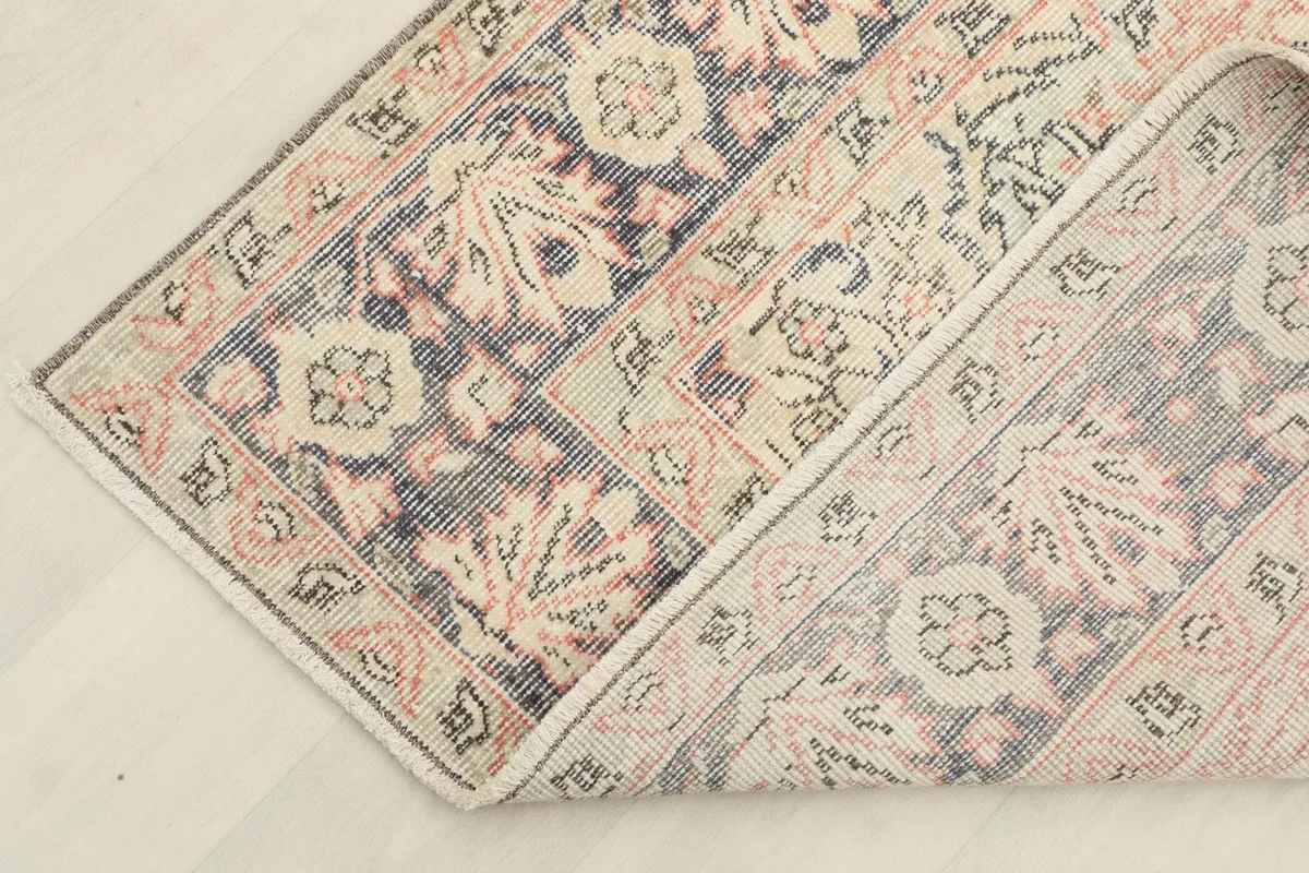 Corner of the rug folded to reveal the cotton foundation and hand-knotted construction.