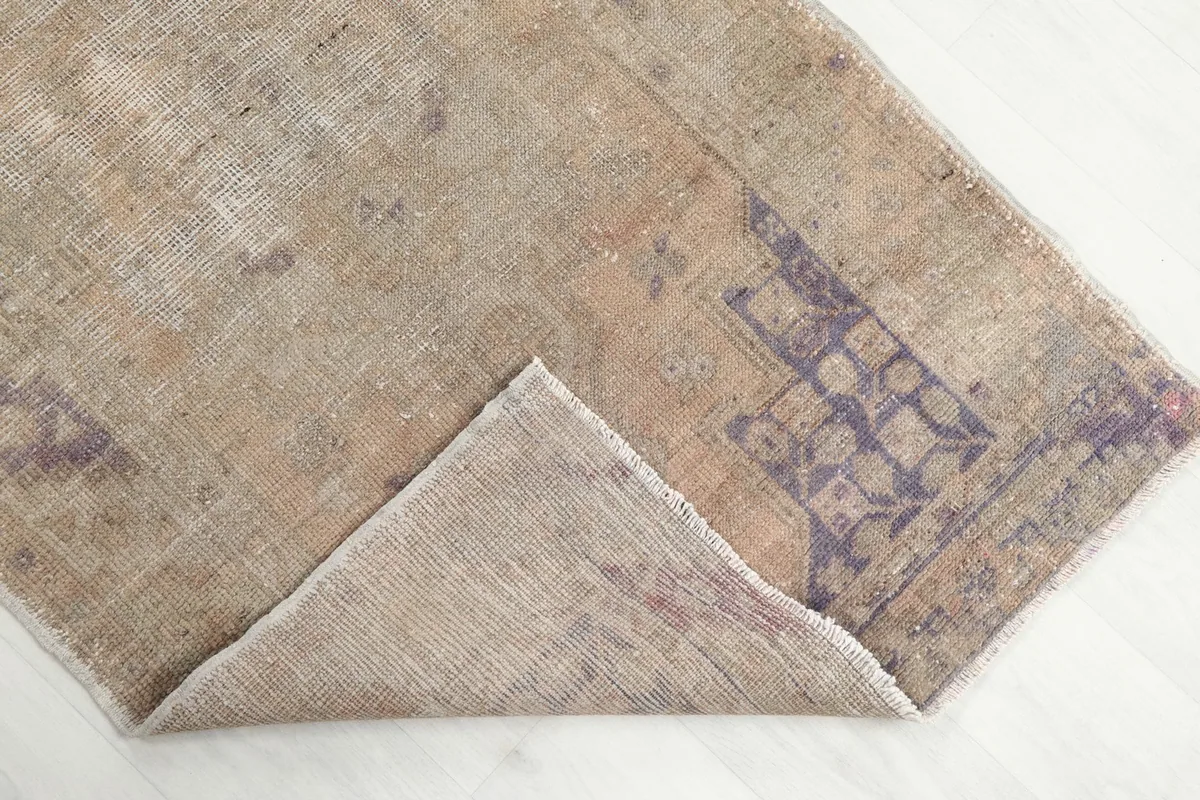 Corner of the rug folded back to reveal the back of the hand-knotted cotton foundation