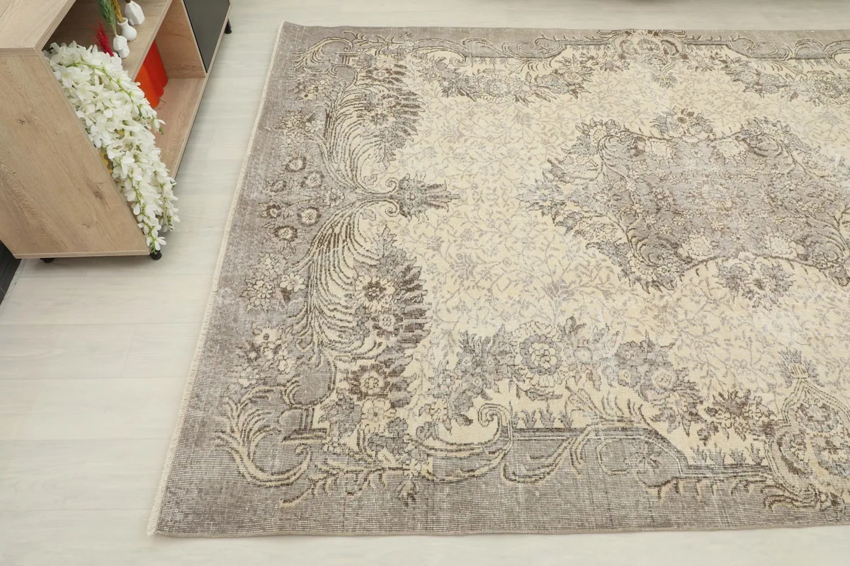 Another angled view of the vintage rug, capturing the intricate gray and beige patterns near the edge.