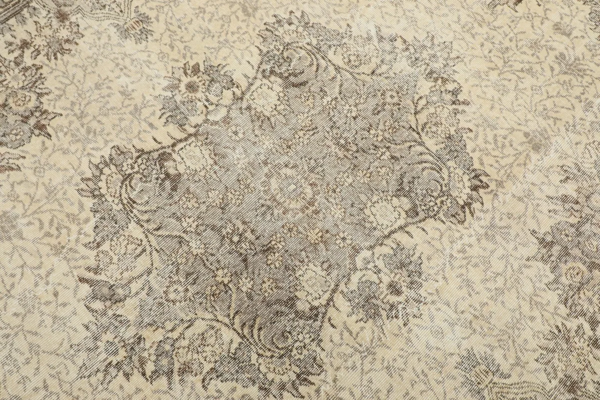Close-up detail of the central medallion design on the ivory field of the vintage rug.