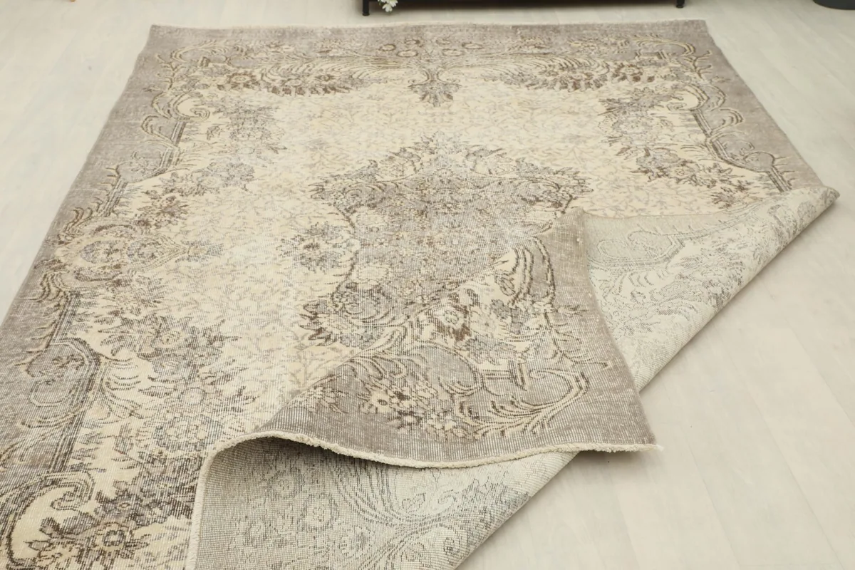 The vintage rug partially folded, displaying both the top surface and the underside.
