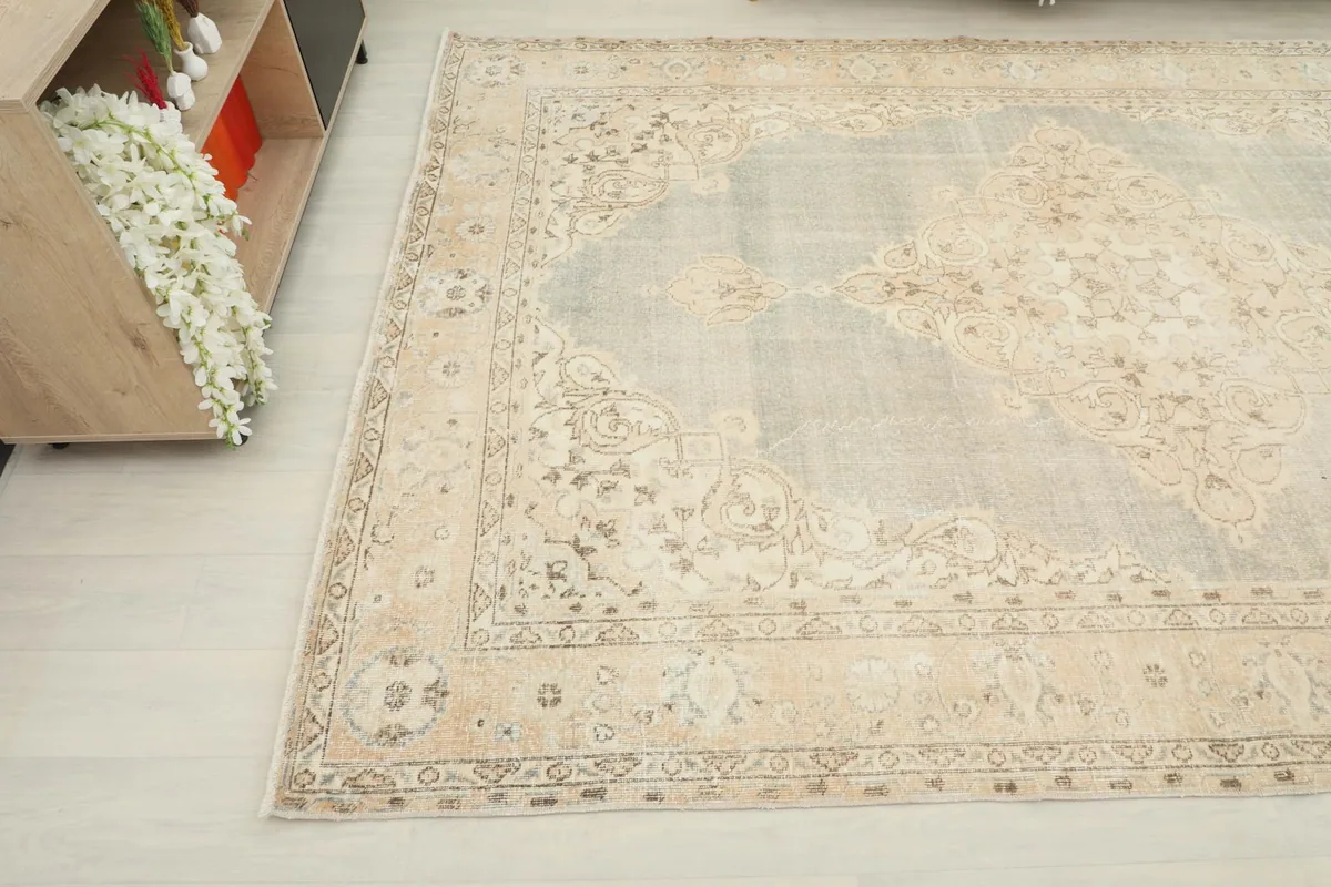Corner view of the rug, showing the intricate beige floral patterns within the main border