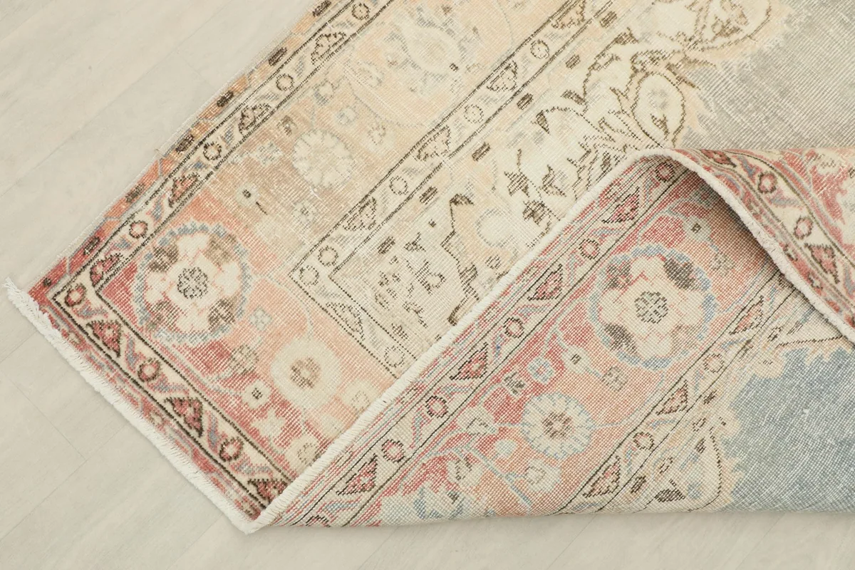 Corner of the rug folded, showing the tight knotting on the back and the fringe detail