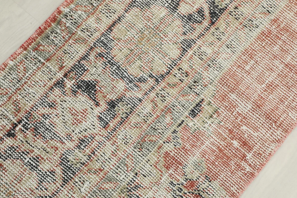 Macro view of the rug's low wool pile, showing the texture and muted colors of the vintage knots.