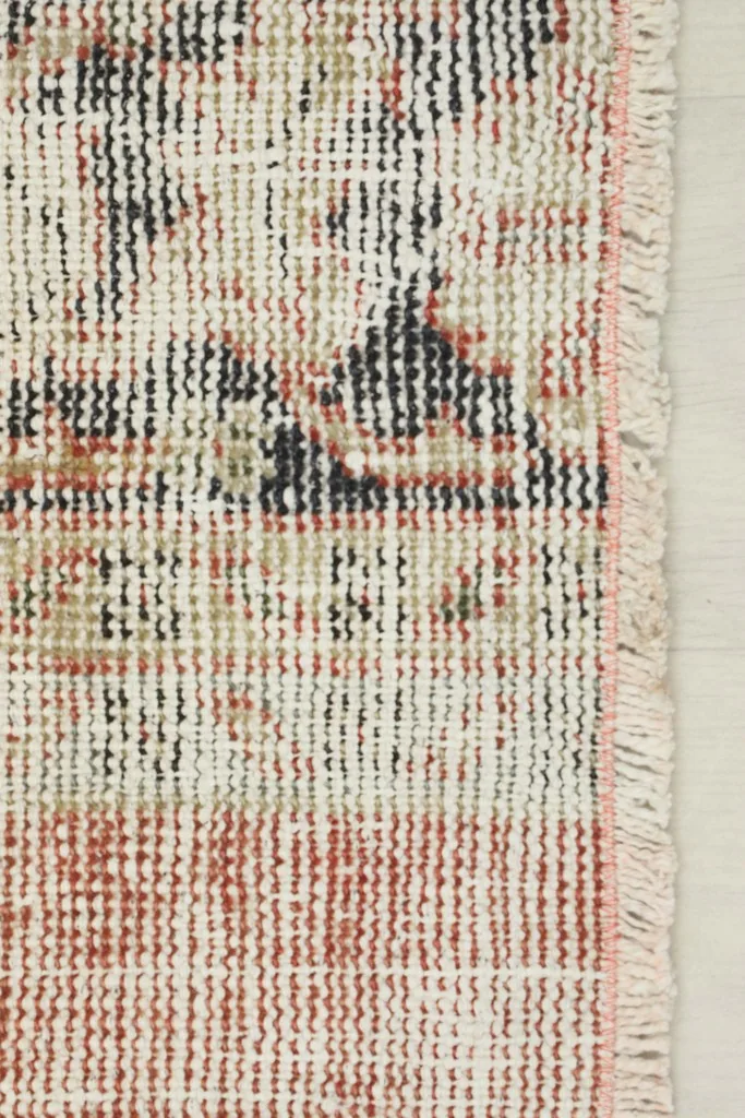Close-up of the rug's short fringe and edge, showing the cotton foundation and wool pile.