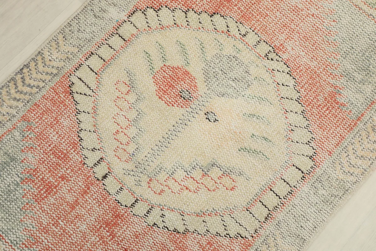 Angled close-up of the rug's central medallion and surrounding orange field with tribal motifs.
