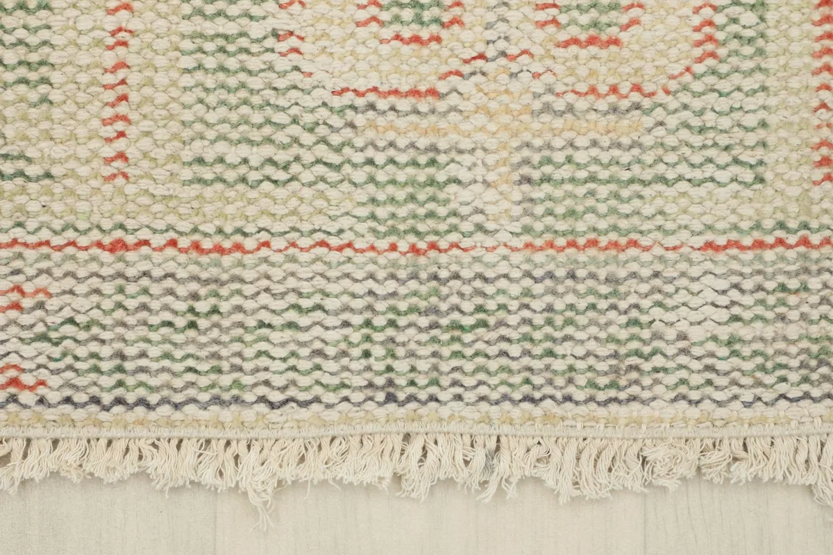 Close-up of the rug's short fringe and the tightly woven edge.