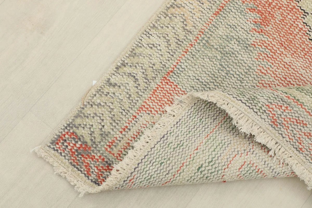 Angled view showing a folded corner of the rug, revealing the wool pile and cotton foundation.