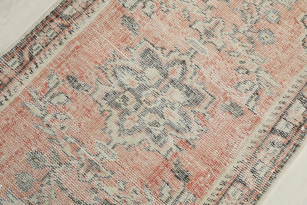 Detailed view of the central medallion design on the orange vintage rug, showing gray and beige tones.