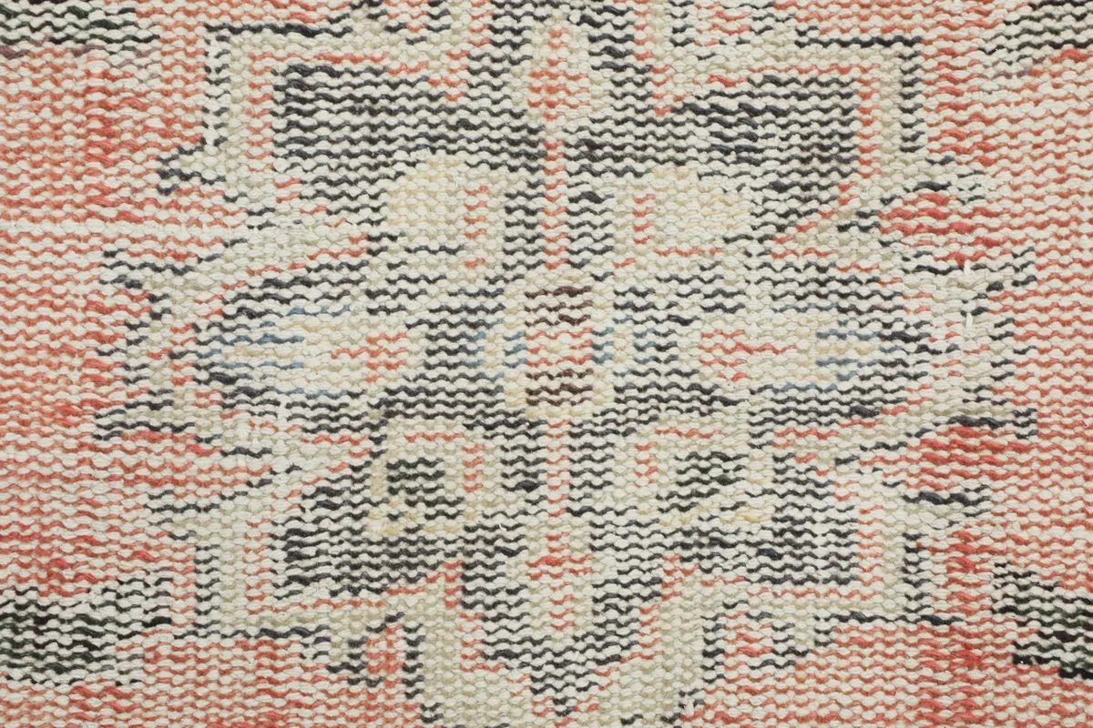 Macro view of the hand-knotted wool pile, showing the texture and weave of the orange and gray vintage rug.