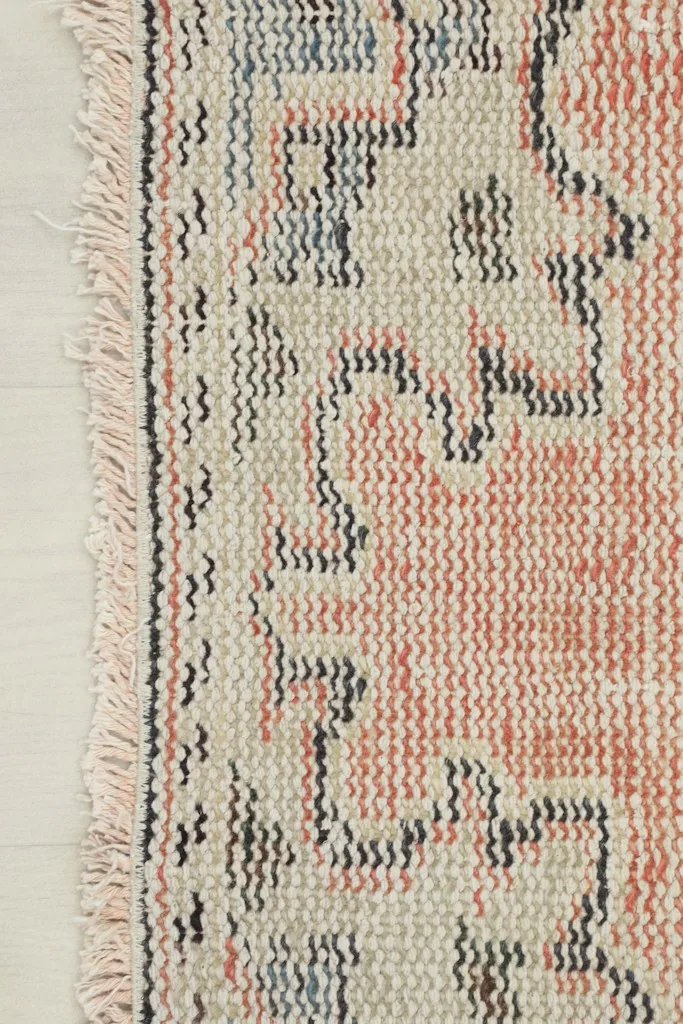Close-up of the rug's edge, highlighting the short, natural fringe and the tight weave.