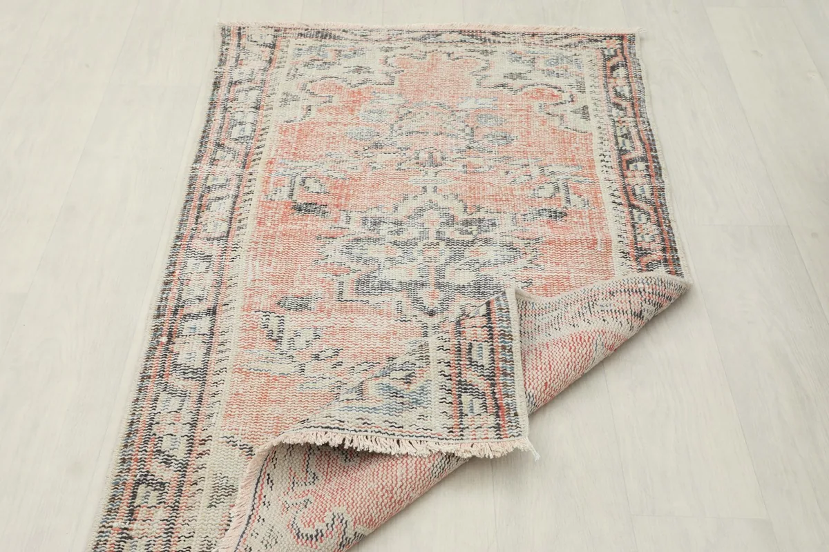 Side of the vintage rug folded back, revealing the backing and construction details.