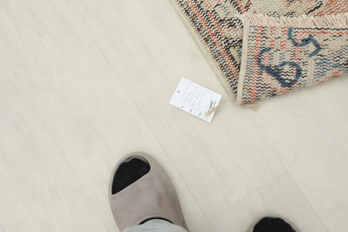Overhead view of the rug with a size tag and feet for scale reference.