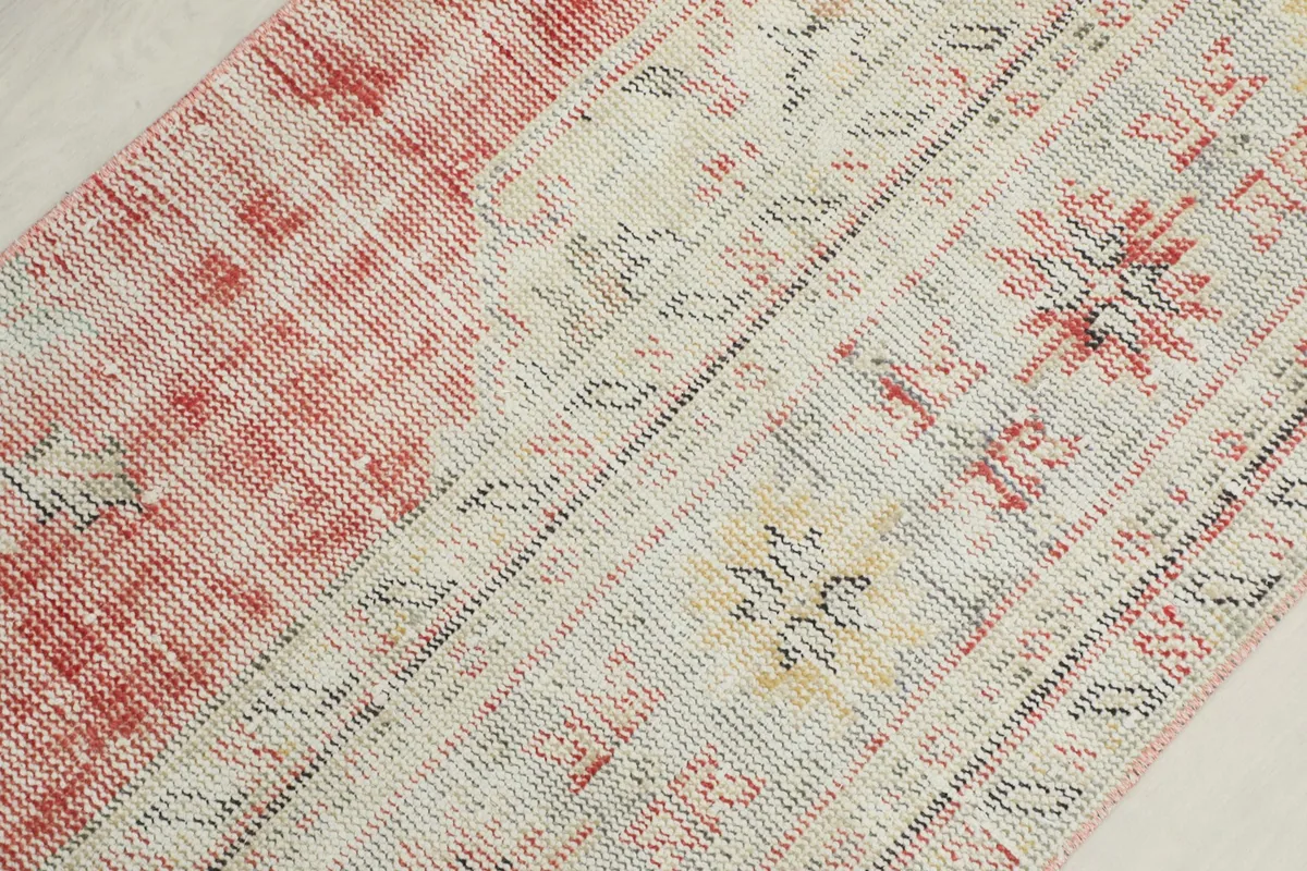 Detailed view of the rug's surface, showing the blend of cream, rose, yellow, and gray fibers