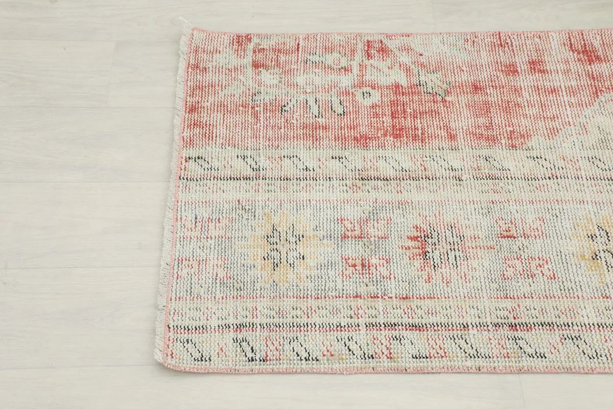 Detail of the rug's border, showcasing the patterns and the transition from cream to rose tones