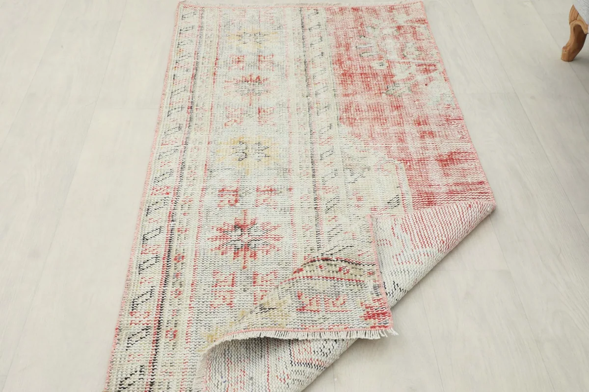 The vintage rug folded back to reveal the full design and the sturdy hand-knotted construction