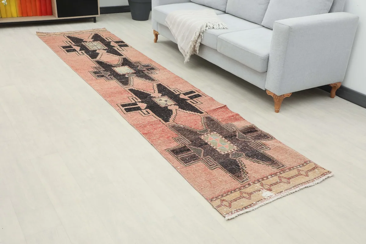 Angled view of the rose and black runner rug in a room, highlighting its length and pattern.
