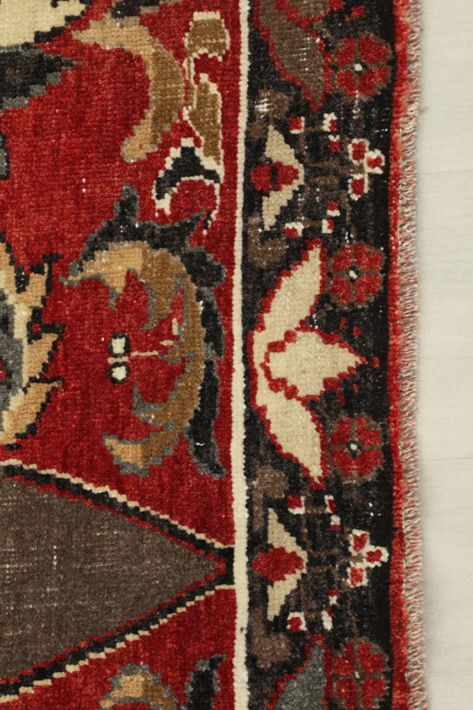 Close-up of the outer black border with small ivory and red floral motifs and fringe