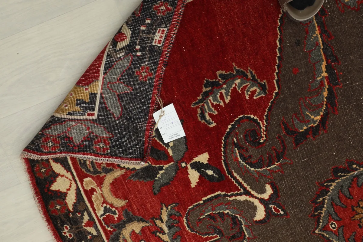 Close-up of the rug's backside, showing the hand-knotted cotton foundation and a tag