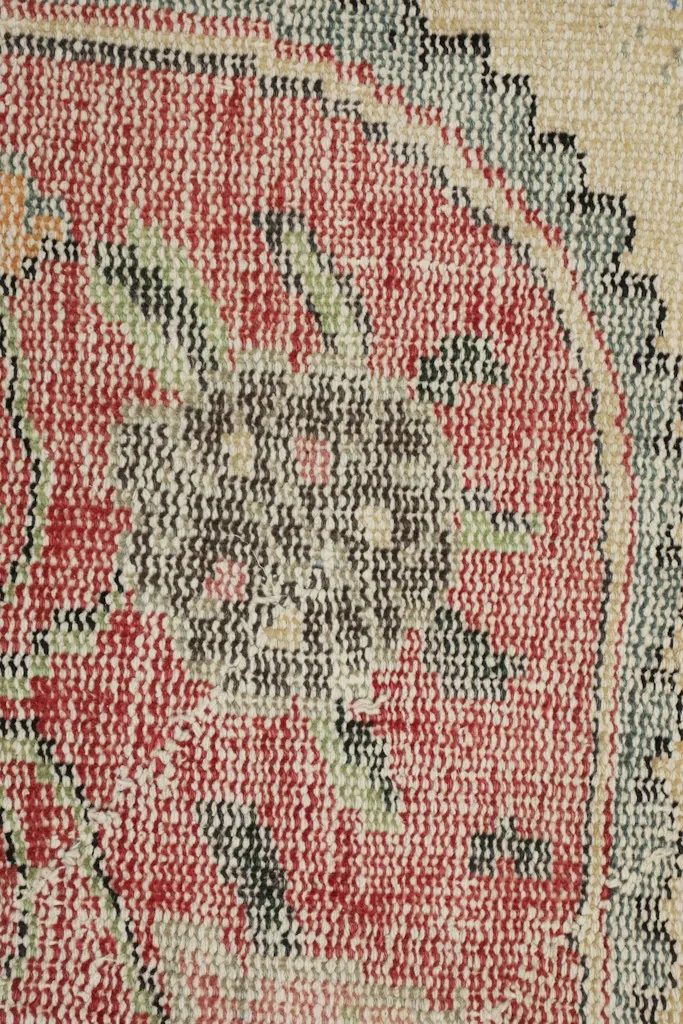 Extreme close-up showing the low wool pile and intricate knotting of the rug.