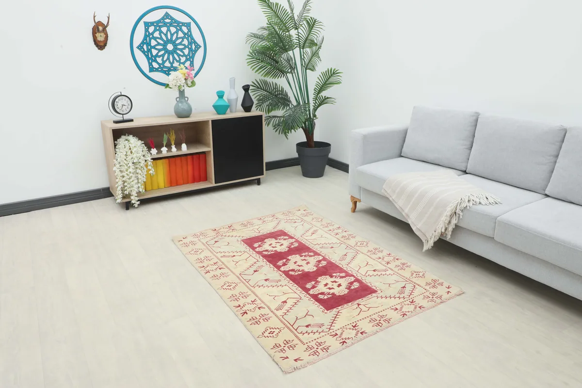 Rose Geometric Anatolian Rug in a room setting, positioned in front of a gray sofa and wooden cabinet.