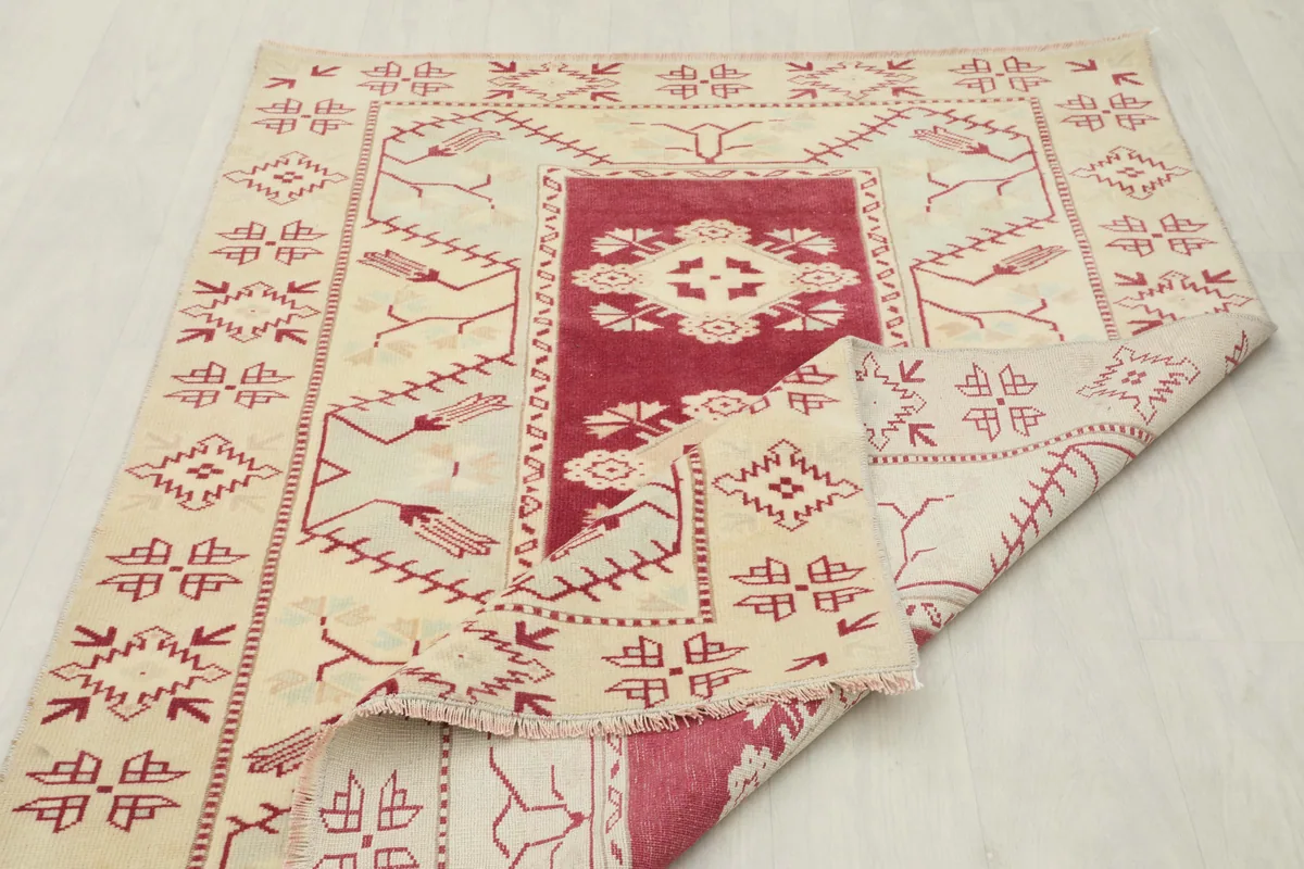 Rose Geometric Anatolian Rug partially folded, showcasing the reverse side and overall design from an angle.