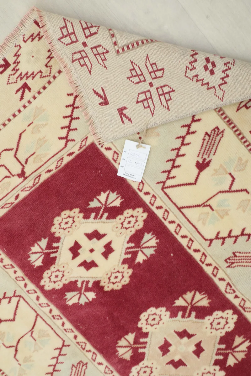 Rose Geometric Anatolian Rug with a tag visible, showing the texture and design up close.