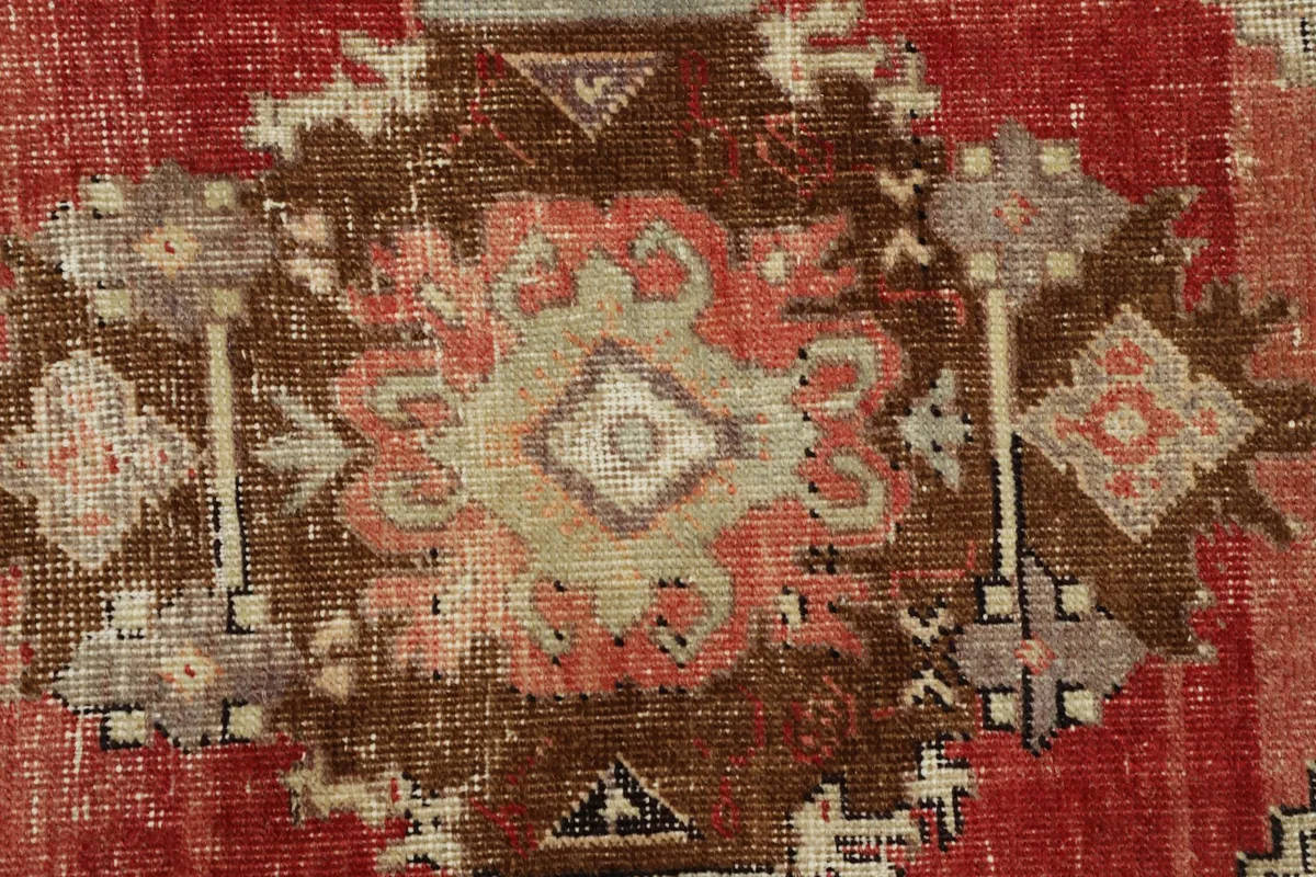 Macro close-up of the rug's central design, showing texture, colors, and hand-knotted wool fibers