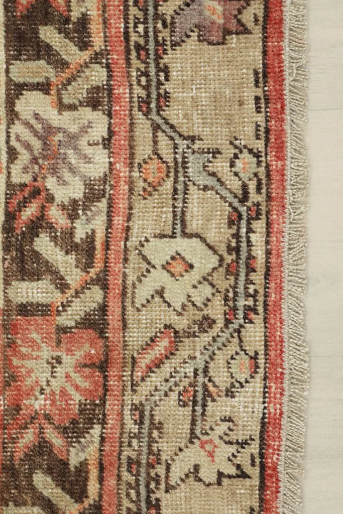 Close-up of the rug's side border, displaying intricate patterns and fringe