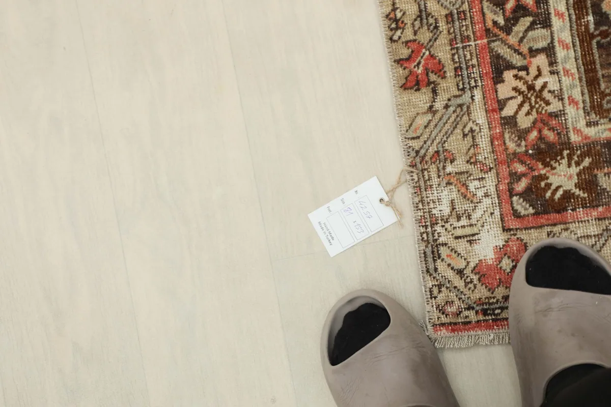 Overhead view of a corner of the rug next to feet, showing the size and a product tag