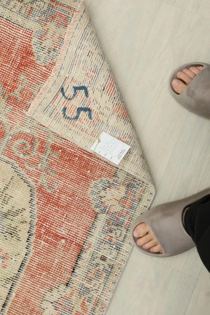 View of the rug's back, revealing the hand-knotted cotton foundation and a size label
