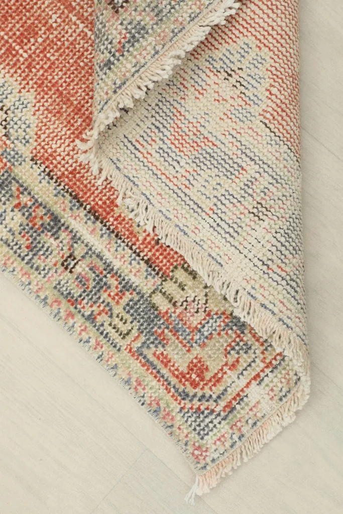 Corner of the rug folded back, showing the cotton foundation and the reverse side of the knots