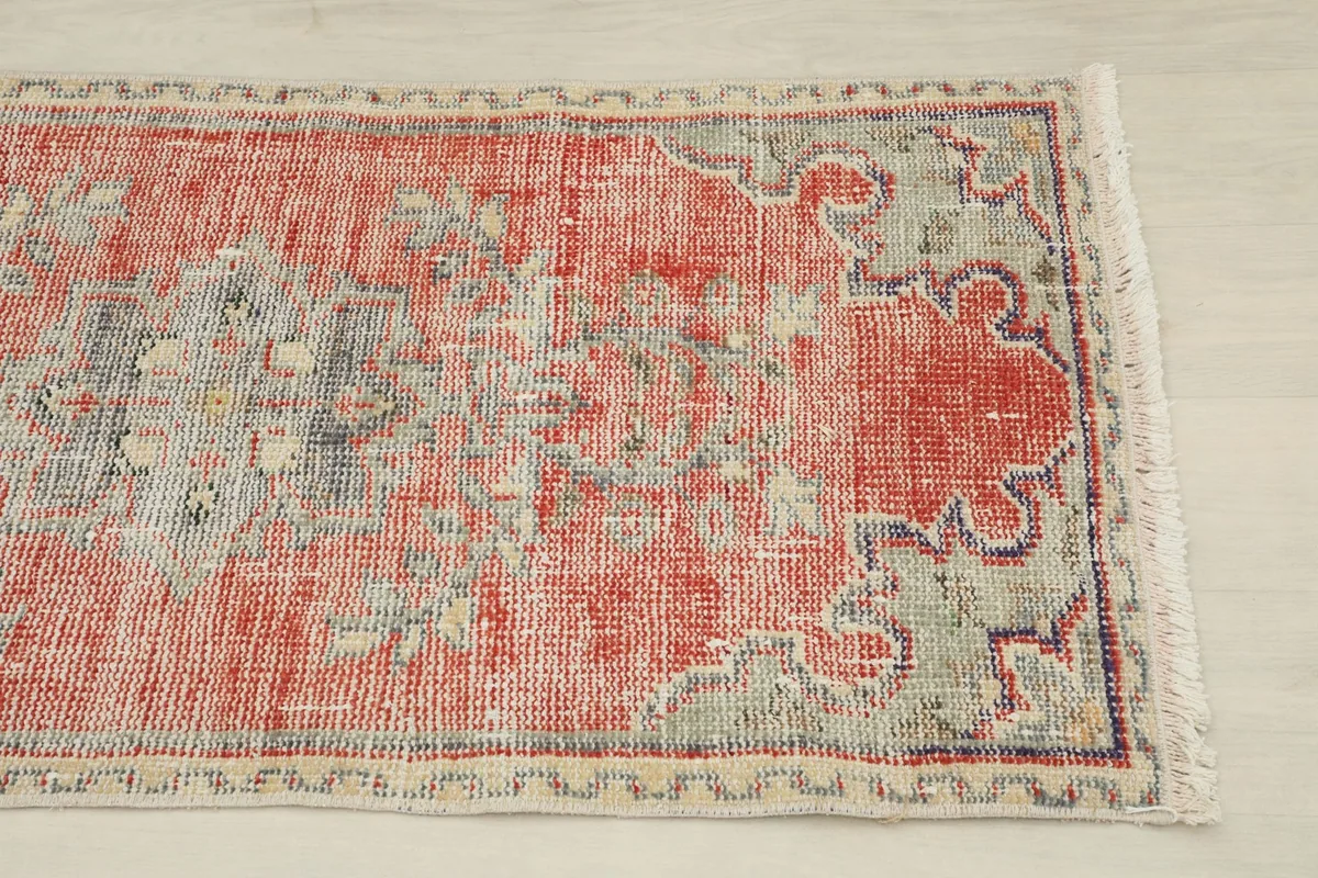 Close-up of the upper right section of the red rug, highlighting the geometric patterns and border.