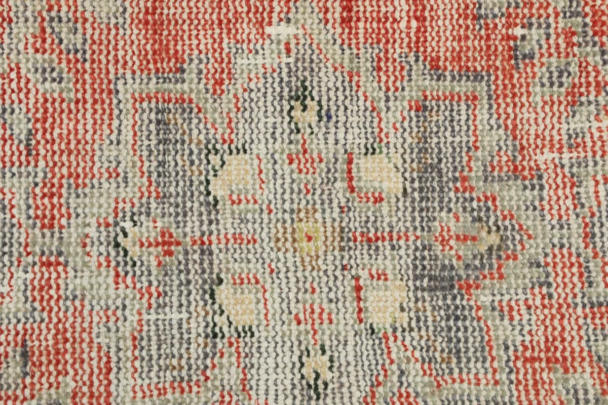 Extreme close-up of the rug's low wool pile, showing the texture and color variations from wear.