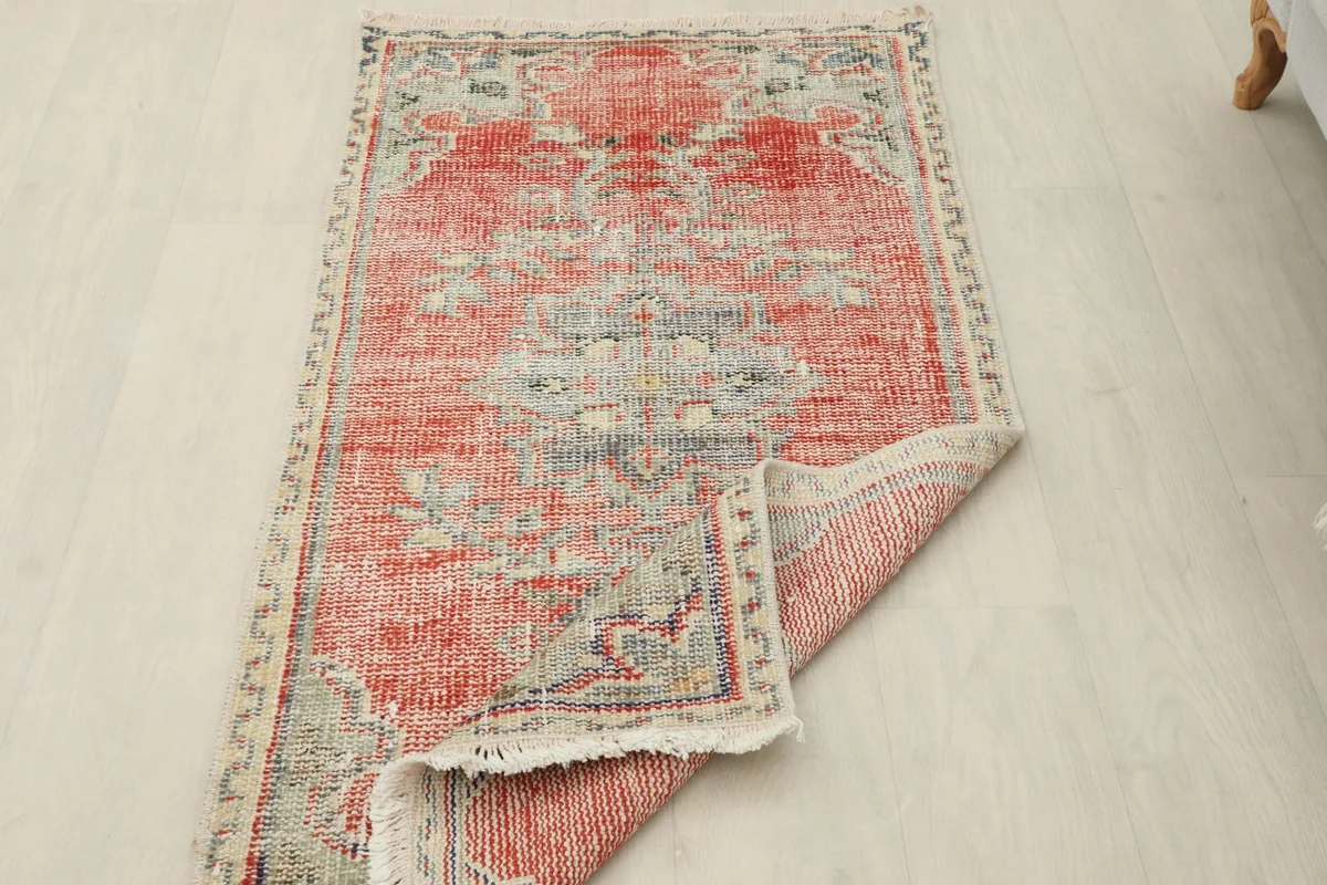 View of the rug with one corner folded, showing the hand-knotted construction on the back.