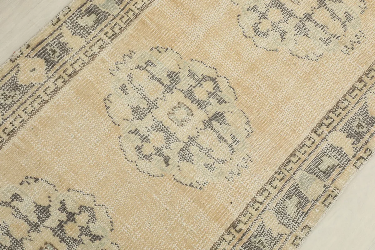 Detailed view of a single gray geometric medallion motif on the beige rug field