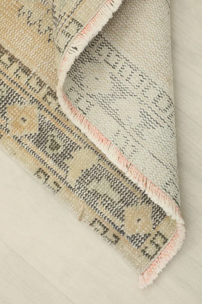 Corner of the rug folded to reveal the hand-knotted cotton foundation and reverse side