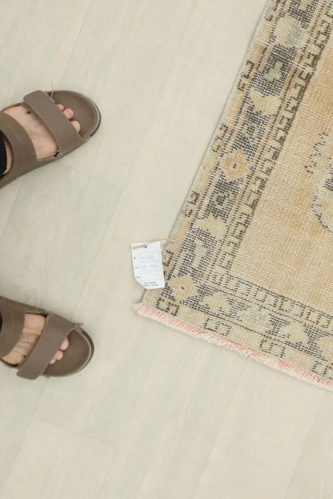 Overhead view of the rug's end with a size tag, alongside feet for scale