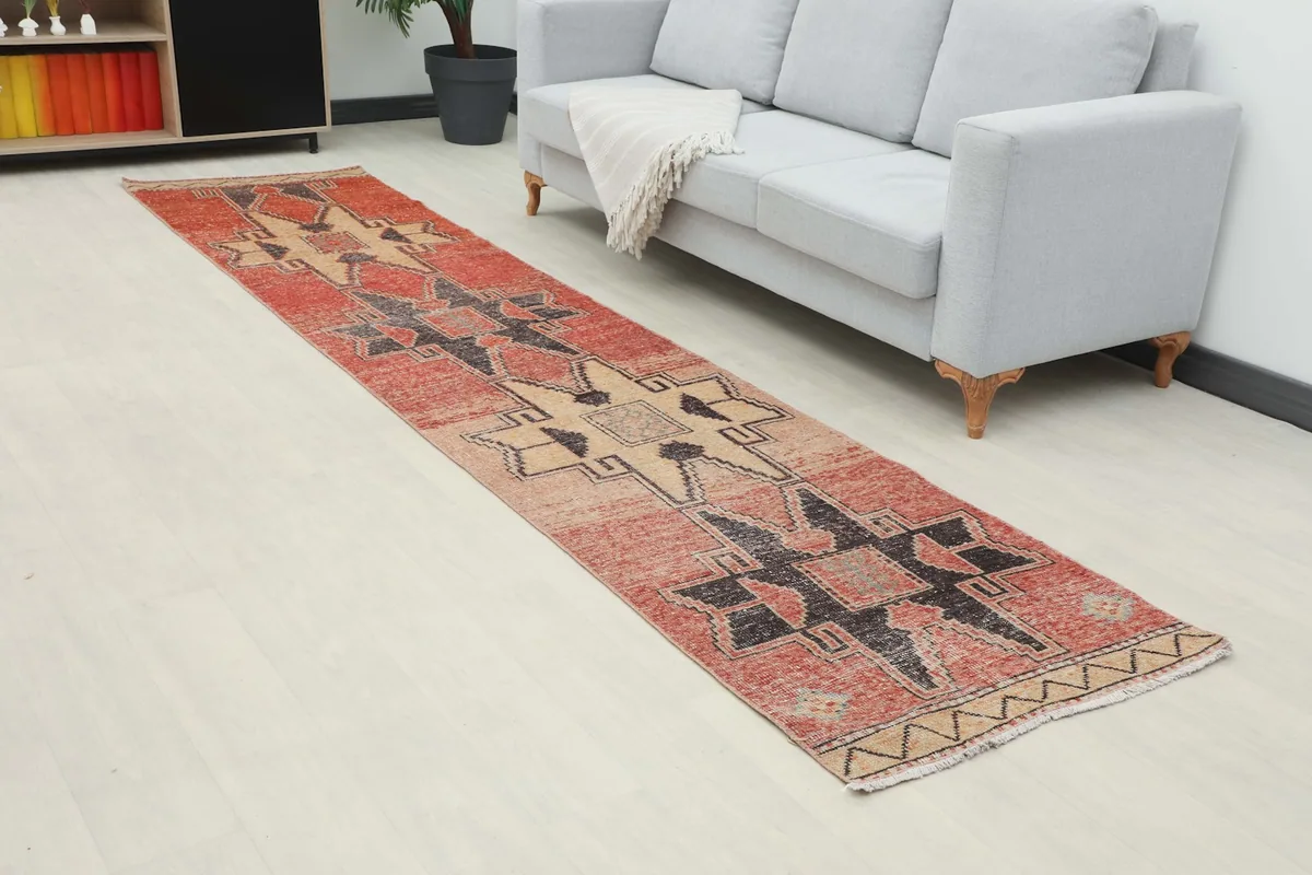 Angle view of the rust and tan runner rug extending from a sofa, highlighting its length and pattern.