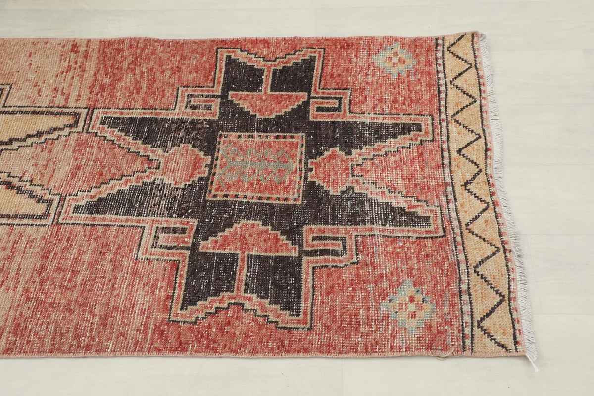 Close-up of the rug's geometric pattern in rust, tan, and charcoal, showing texture and color variations.