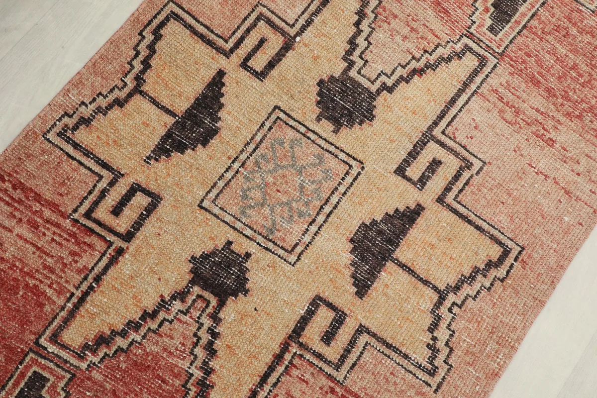 Detailed view of a central tan geometric motif with charcoal outlines and a subtle patterned square.