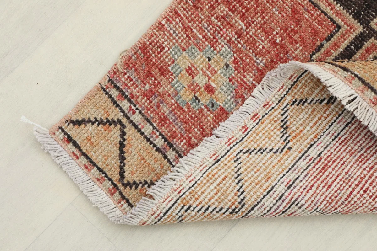 View of the rug's corner folded to show the hand-knotted wool pile on a cotton foundation from the back.