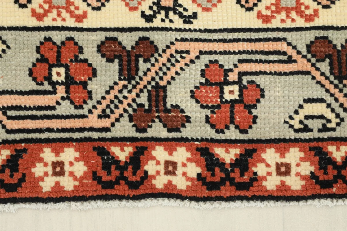 Close-up of the rug's border, featuring a geometric design in gray, rust, and black.