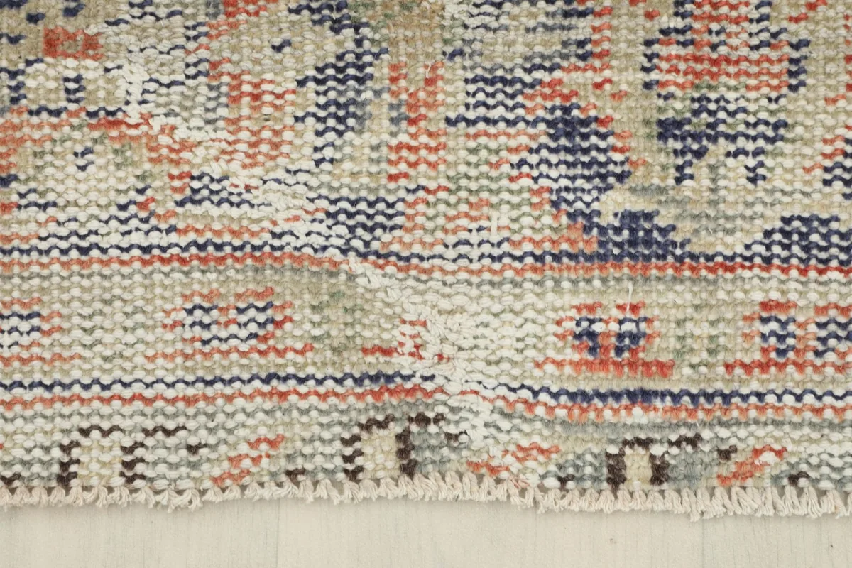 Close-up of the short, natural cream fringe and edge finishing of the hand-knotted rug.