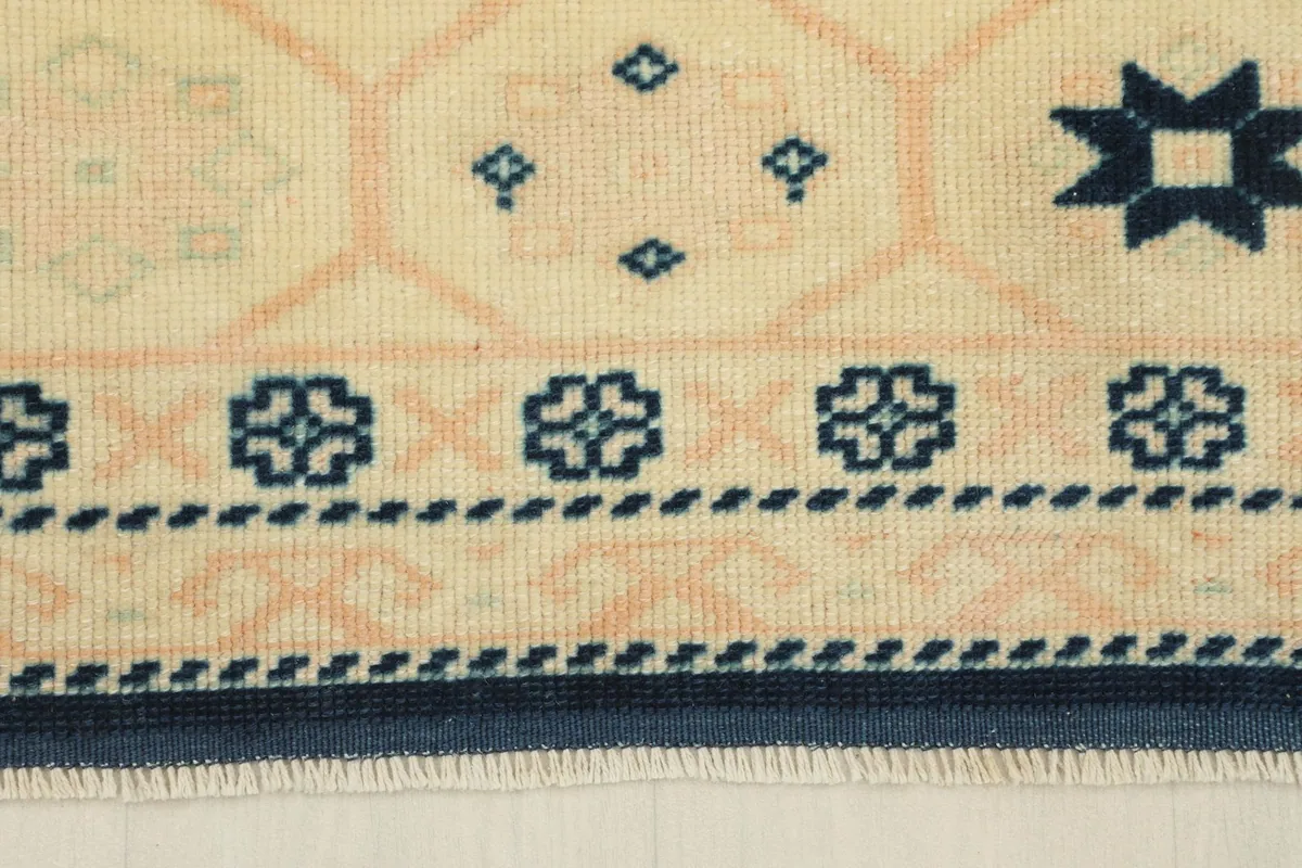 Close-up of the rug's beige border with small navy floral and geometric elements