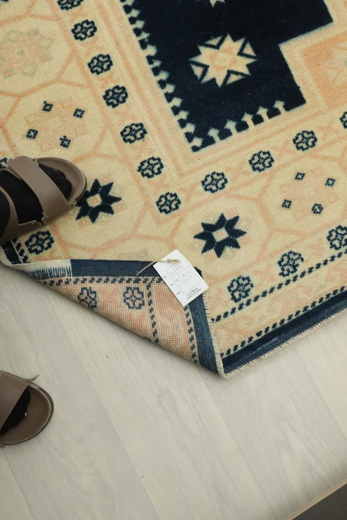 View of the rug's label and texture near the fringe, with slippers for scale