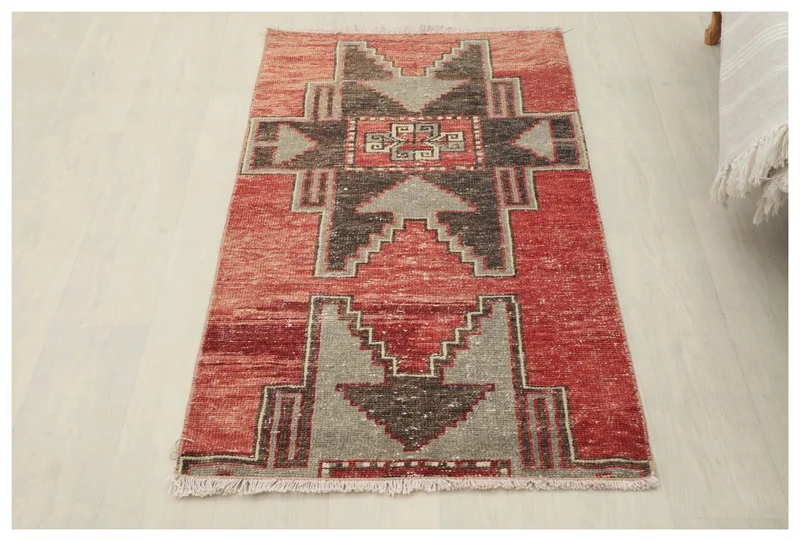 Full top view of the red and charcoal geometric vintage Anatolian rug on a white floor