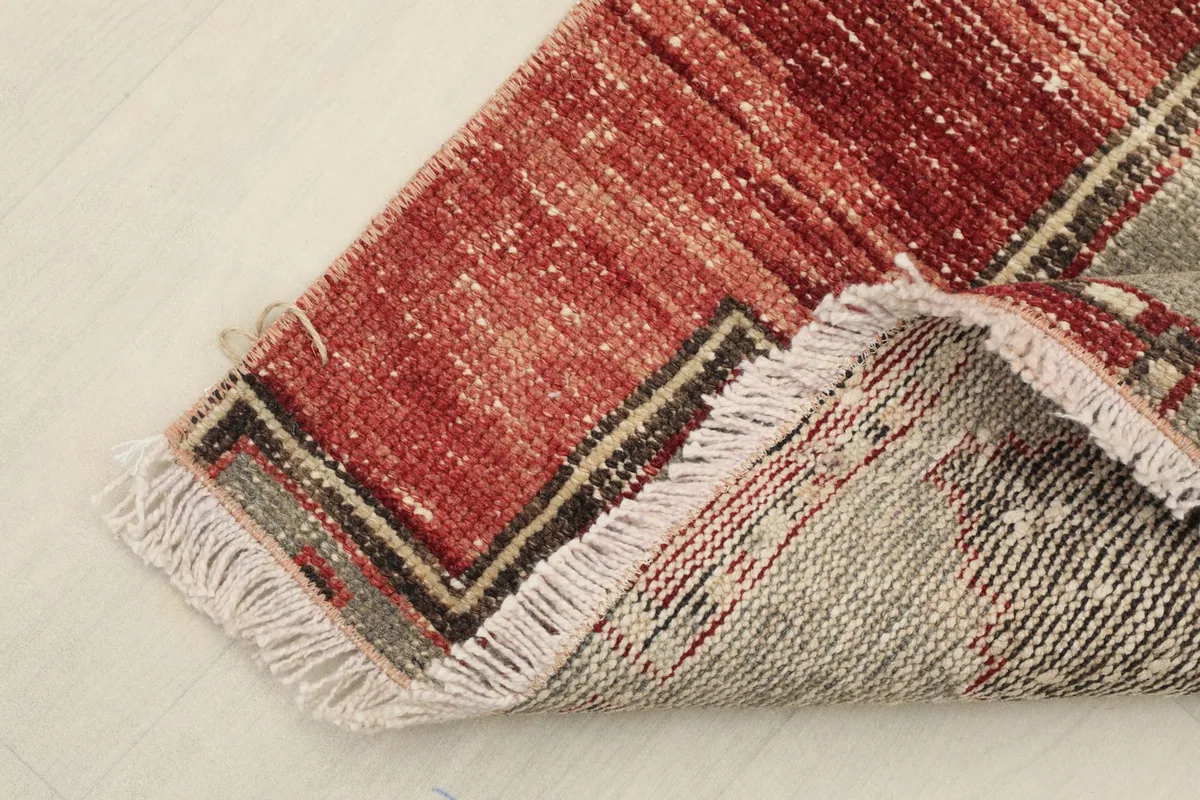 Close-up of the rug's folded edge, showing the hand-knotted cotton foundation on the reverse